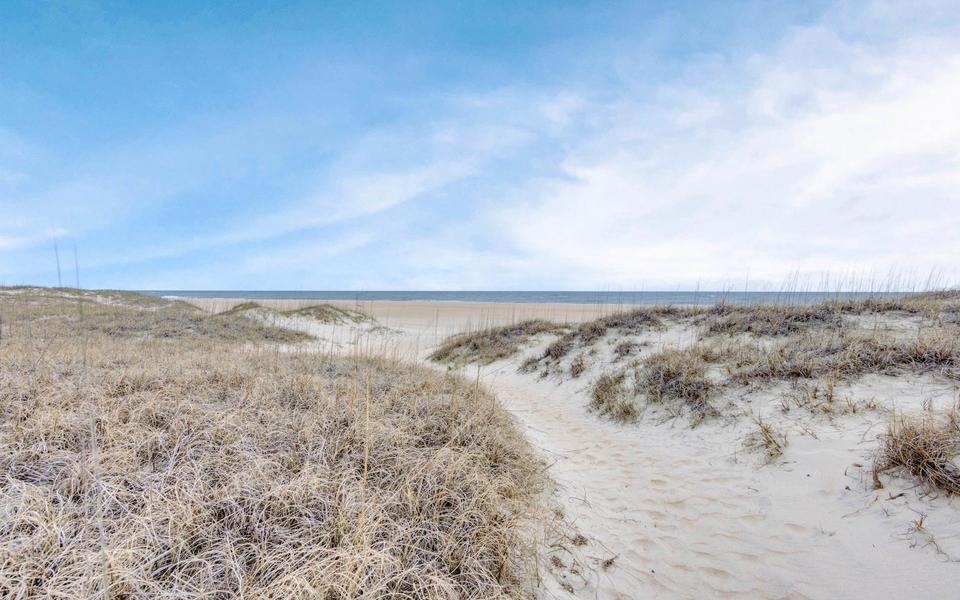 Sand path leading to the ocean flanked by straw-colored winter dune grasses under a blue sky invite you to do winter things