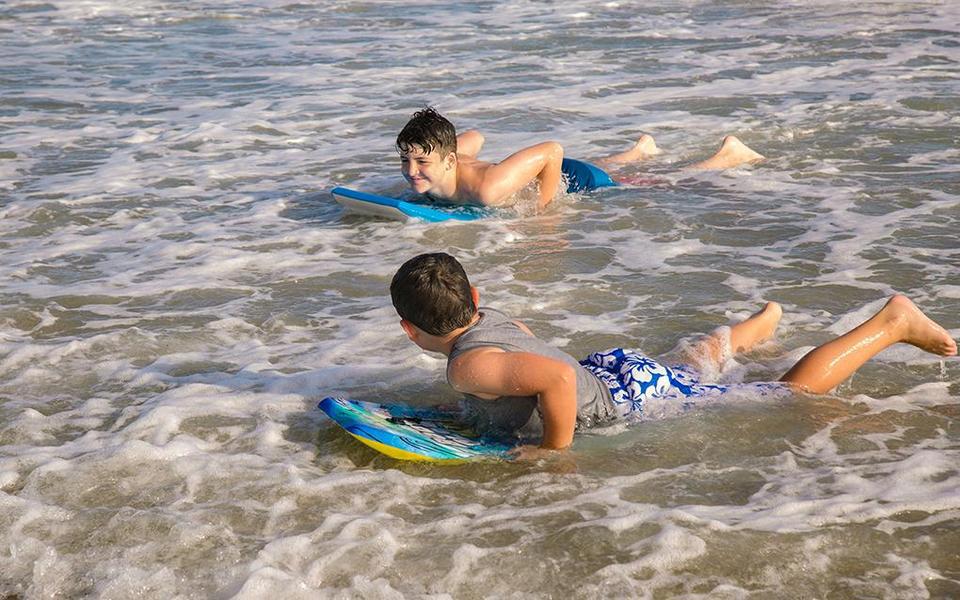 Two children lay on bodyboard in shallow waters during some summertime fun on Hatteras Island