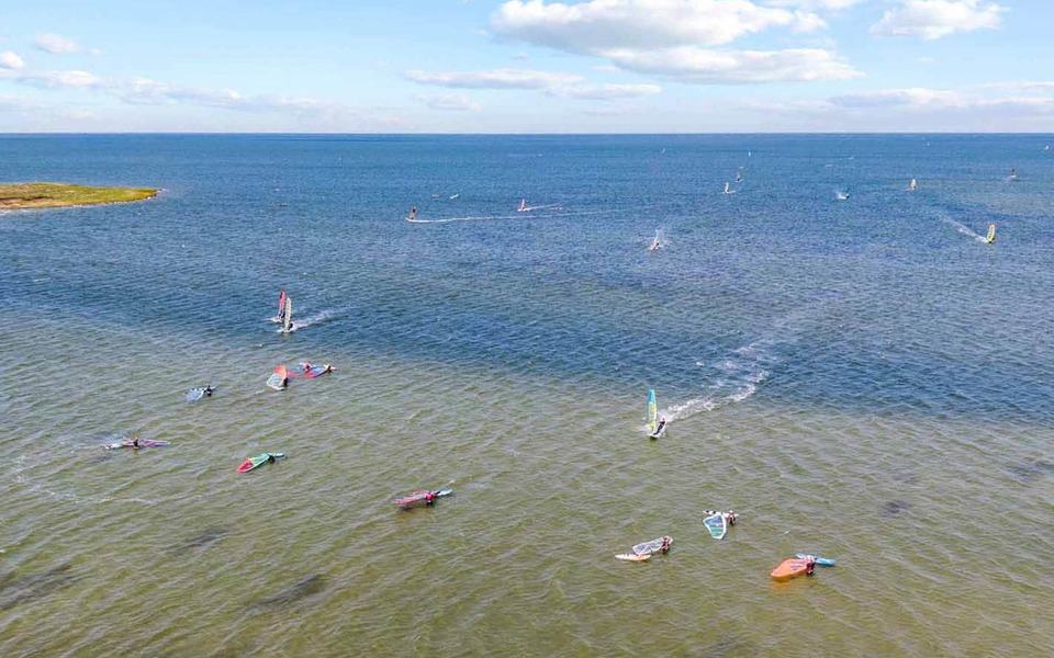 Dozens of windsurfers dot the sound in this aerial drone shot looking out over the Pamilco Sound from Avon