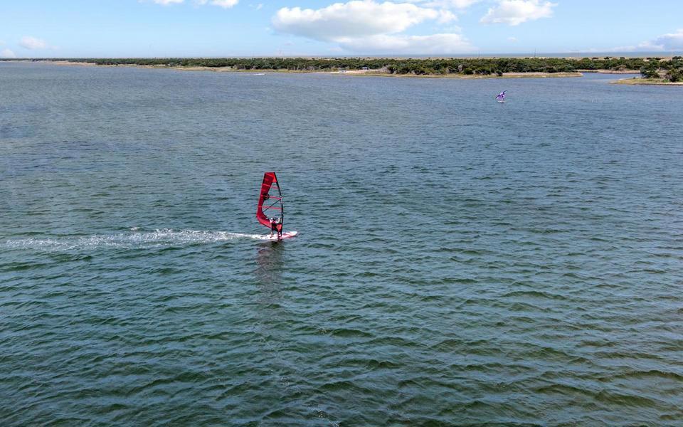 A single pink windsurfer tracks across a wide expanse of the Pamilco Sound