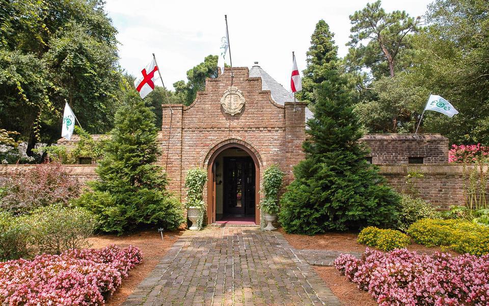 A brick walkway leads to a door with a rounded top at the entrance to the Elizabethan Gardens in Manteo, NC