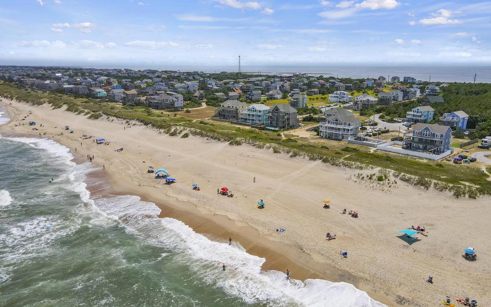 High drone shot of beachgoers on a Hatteras Island beach. We promote vacations here as part of our jobs