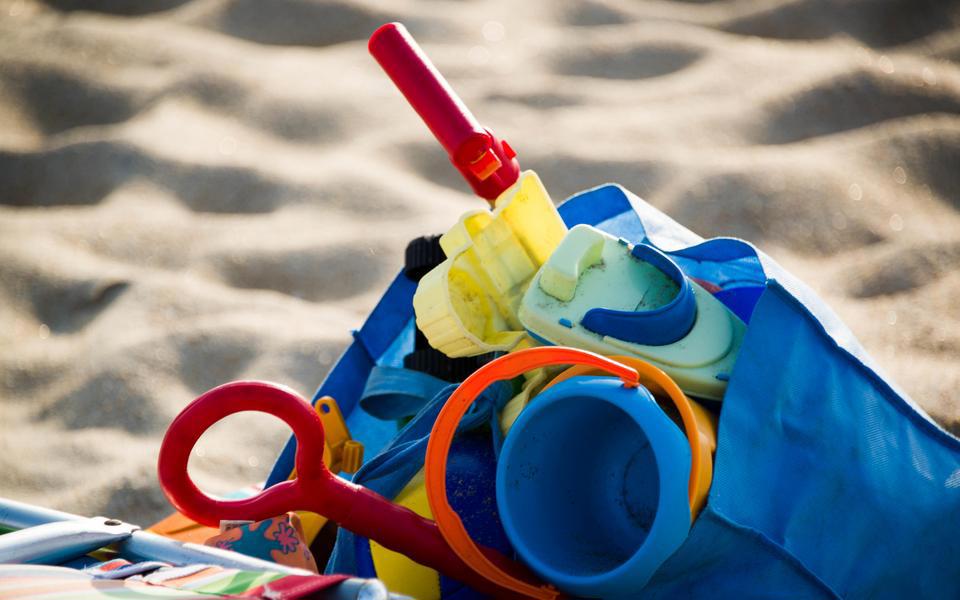 Beach toys fill a blue beach back with a sandy beach in the background on Hatteras Island