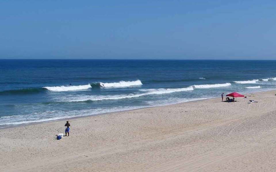Just a few people on a vast stretch of beach with gentle waves rolling in alone the Tri-Villages - Rodanthe, Waves, & Salvo