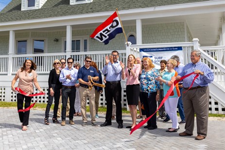 Joined with members of the Chamber of Commerce and Surf or Sound Realty's Executive Team; Dale Petty, owner, cuts the ribbon to officially open the Hatteras Village office of Surf or Sound Realty.