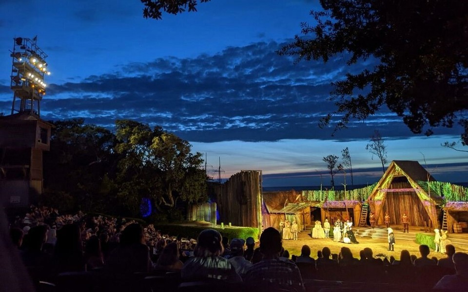 The Lost Colony mid-production under the lights at twilight from the back right of the outdoor theater in Manteo