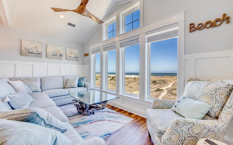 Airy light colored Hatteras Island vacation home great room with a spring beach scene outside four large windows