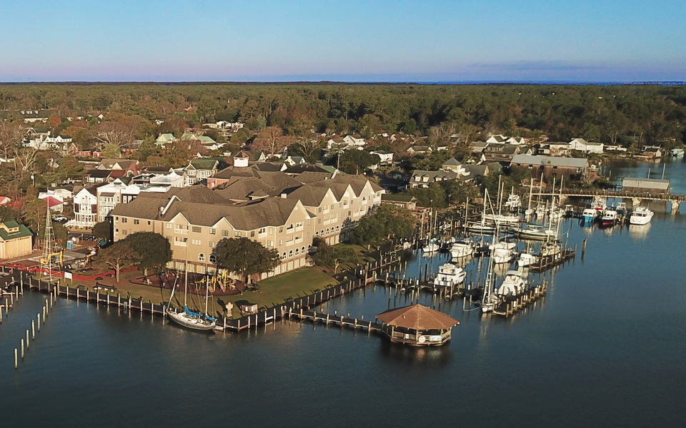 Drone view of the northern corner of the Manteo waterfront and boardwalk. Sailboats dot the marina on the left. 