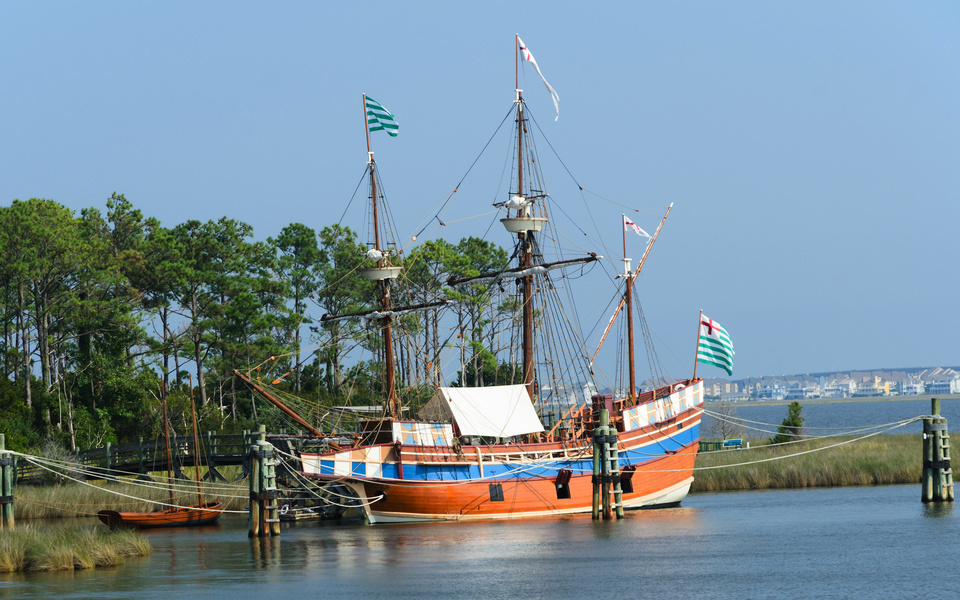 The three masted schooner, The Elizabeth II, docked at Festival Park across from downtown Manteo bathed in sunlight