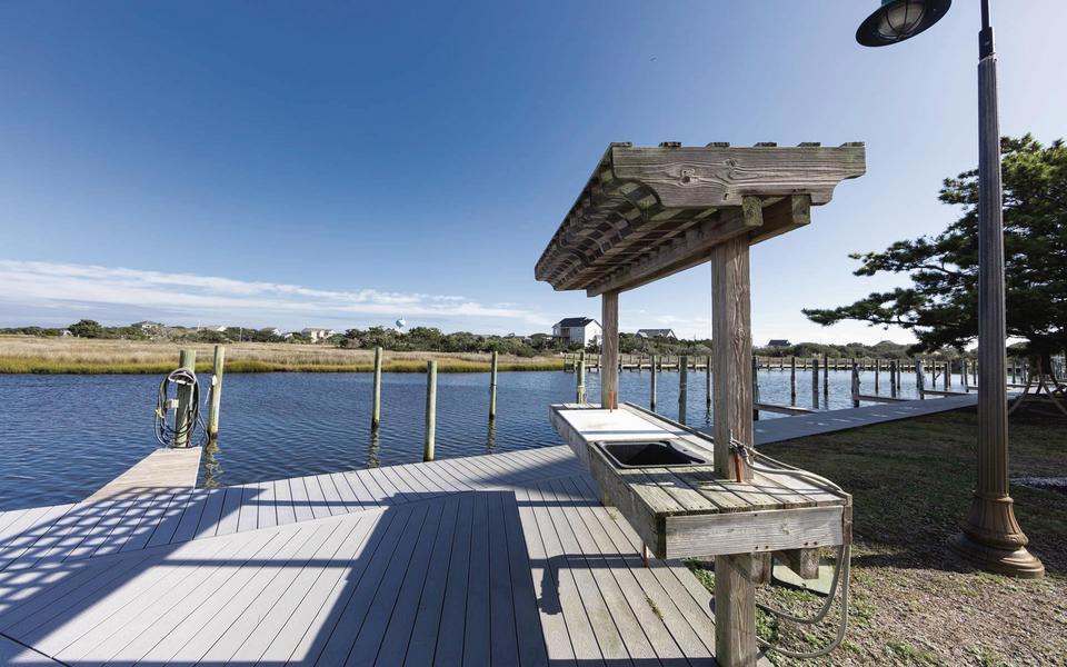 A shaded fish cleaning station on a dock - with water and marsh grasses in the background under a deep blue sky