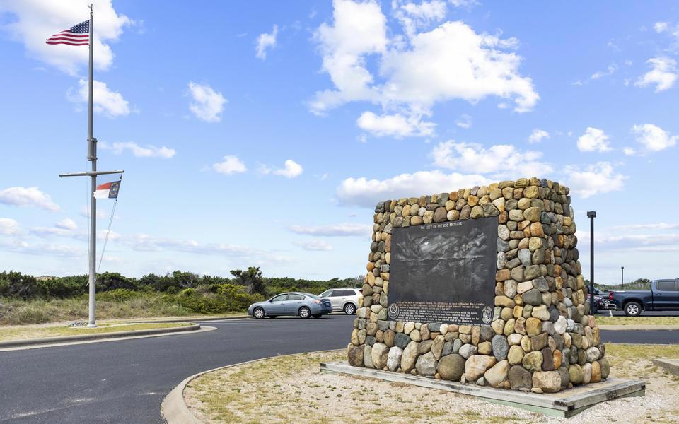 Large black stone informational plaque on a rock obelisk in the parking area of the Graveyard of the Atlantic Museum