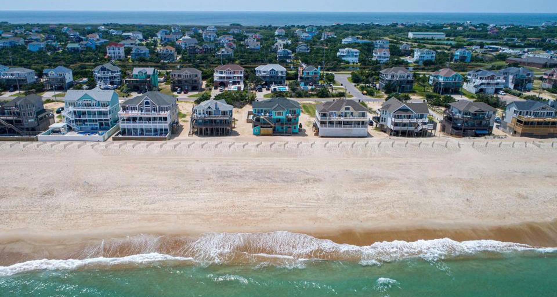 Drone view of a row of oceanfront vacation homes in Avon on Hatteras Island with the ocean in the foreground