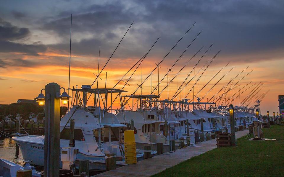 Row of Hatteras-based off-shore charter fishing boats line the dock at Teach's Lair Marina under a fall pre-dawn sky