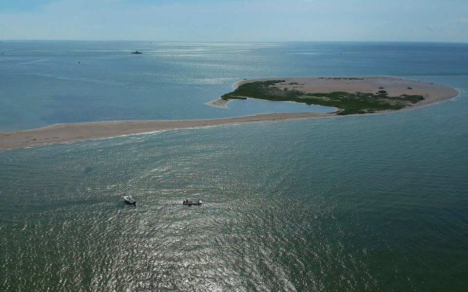 Plane or drone shot from very high of two dots of dolphin tour boats near an uninhabited island